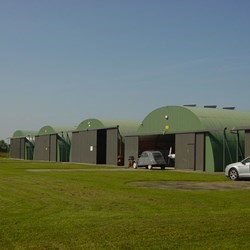 linha de 5 telhados redondos tipo omega num campo de aviação