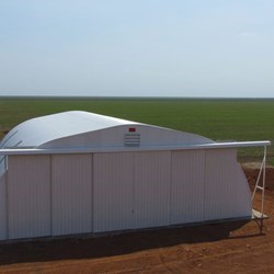 Vista exterior geral do hangar fechado com o avião seguro dentro, a cor branca pré-pintada reflete ao máximo o calor do sol.