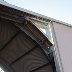 Vista detalhada das portas na posição aberta e a viga do trilho do qual estão pendentes.