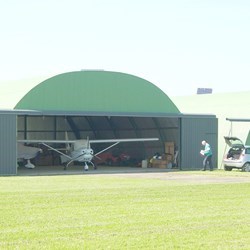 omega steel airport hangar with doors open, showing 2 airplanes parked inside