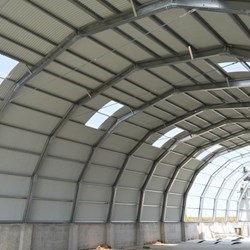 um novo Frisomat Omega + em construção: vista interior da chapa ondulada, dos pórticos de aço galvanizado e do muro de contenção