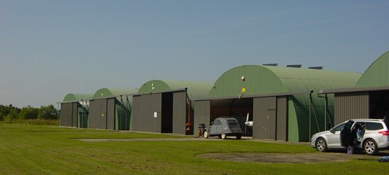 5 hangares Frisomat Omega em uma fileira, utilizados para guardar aviões em um aeródromo no norte da França.